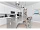 Modern kitchen island has seating and stylish pendant lighting alongside stainless steel appliances and white cabinets at 7770 Sandy Ridge Dr # 142, Kissimmee, FL 34747