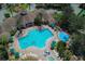Aerial view of a large community pool surrounded by lounge chairs, umbrellas, lush landscaping and an adjacent clubhouse at 8121 Fan Palm Way, Kissimmee, FL 34747
