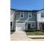 Two-story townhome featuring a one-car garage, solar panels, manicured lawn, and neutral paint at 892 Grandin St, Davenport, FL 33837