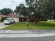 Charming one-story home with a large tree in front and a well-maintained lawn and a white SUV in the driveway at 925 Derbyshire Dr, Kissimmee, FL 34758
