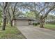 Single-story home with stone accents, two-car garage, and mature trees at 9905 Nicoma Ln, Orlando, FL 32817