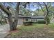Charming single-story home with stone accents, a lush yard, and mature trees providing shade at 9905 Nicoma Ln, Orlando, FL 32817