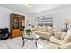 Cozy living room features a patterned sofa, glass coffee table, and display cabinet near a bright window at 1526 Ferendina Dr, Deltona, FL 32725