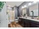 Modern bathroom with dual vanity, a glass-enclosed shower, and wood-look tile floors at 1064 Quaker Ridge Ln, Davenport, FL 33896