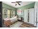 Cozy bedroom with green walls, a large window, a ceiling fan, and light wood-look flooring at 1064 Quaker Ridge Ln, Davenport, FL 33896