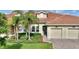 Charming home featuring a red tile roof, a two-car garage and palm trees accenting the landscaped front yard at 1064 Quaker Ridge Ln, Davenport, FL 33896