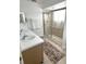 Bathroom featuring a walk-in shower with glass doors, double sinks and soft accent rug at 108 Honeywood Ct, Kissimmee, FL 34743