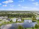 Wide aerial view of a neighborhood, with a focus on the community pond and surrounding greenery at 10950 Belle Maisons Dr, Orlando, FL 32832