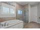 Modern bathroom highlighting a walk-in shower and soaking tub with natural stone tiling at 10950 Belle Maisons Dr, Orlando, FL 32832