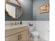 Stylish powder room with decorative mirror, sink vanity, toilet, and gray walls with wainscoting at 10950 Belle Maisons Dr, Orlando, FL 32832