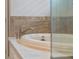 Close up view of a white soaking tub with tile surround and brushed nickel fixtures at 10950 Belle Maisons Dr, Orlando, FL 32832