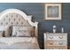 Charming bedroom featuring a tufted headboard, elegant linens, and rustic blue wood paneling at 10950 Belle Maisons Dr, Orlando, FL 32832