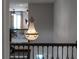 Second-floor view of a ornate chandelier illuminating the landing near the railing at 10950 Belle Maisons Dr, Orlando, FL 32832