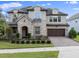 Inviting two-story home boasting a stone facade, arched entryway, and a paver driveway, complemented by manicured landscaping at 10950 Belle Maisons Dr, Orlando, FL 32832