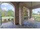 Cozy porch with a charming swing, stone columns, and a paved floor overlooking the landscaped front yard at 10950 Belle Maisons Dr, Orlando, FL 32832