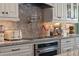 Modern kitchen featuring white cabinets, stainless steel oven and a stylish tile backsplash at 10950 Belle Maisons Dr, Orlando, FL 32832