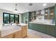 A bright kitchen showcases green cabinets, stainless appliances and an island with sink at 11951 Elbert St, Clermont, FL 34711