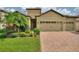 Charming home exterior with a two-car garage, brick driveway, and lush landscaping at 1353 Palmetto Dunes St, Davenport, FL 33836