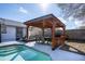 Backyard view of the covered outdoor dining area with a built-in grill near the refreshing in-ground pool at 1375 Springfield St, Kissimmee, FL 34744