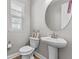 Cozy half bathroom featuring a pedestal sink, round mirror, and a window for natural lighting at 1379 Kiawah St, Celebration, FL 34747
