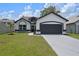 Charming single-story home with a two-car garage, well-manicured lawn, and black and white color scheme at 14639 Musket Fire Ln, Orlando, FL 32837