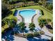 Aerial view of community pool, lush landscaping, lounge seating, and paved deck at 148 Whirlaway Dr, Davenport, FL 33837