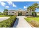 Community center entrance with landscaped bushes, lush grass, and large palm trees at 148 Whirlaway Dr, Davenport, FL 33837