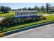 Entrance sign for Champions Reserve surrounded by grass, plants and flowers at 148 Whirlaway Dr, Davenport, FL 33837