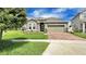 Attractive home featuring stone detailing, a two-car garage, and a brick driveway, set in a landscaped yard at 148 Whirlaway Dr, Davenport, FL 33837