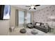 The stylish living room features modern wallpaper, gray sofa, throw pillows, a ceiling fan, and neutral gray walls at 148 Whirlaway Dr, Davenport, FL 33837