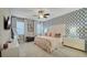 Stylish main bedroom with patterned accent wall, ceiling fan, neutral window treatments, and tiled flooring at 148 Whirlaway Dr, Davenport, FL 33837