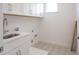 Well-lit laundry room with patterned tile flooring, shaker cabinets, and stainless steel sink and faucet at 15600 Vetta Dr, Bella Collina, FL 34756