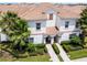 Well-maintained townhouses with red tile roofs, manicured landscaping, and charming architectural details under a blue sky at 1565 Plunker Dr, Davenport, FL 33896