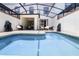 In-ground pool with clear blue water, surrounded by a patio, furniture, and a screened enclosure for outdoor enjoyment at 1565 Plunker Dr, Davenport, FL 33896