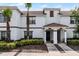 Townhome exterior featuring white facade, brown trim, tiled roof and manicured landscaping at 1578 Slice Way, Davenport, FL 33896