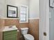 Cozy half bathroom features a green vanity, framed mirror, and brown tiled walls at 16 Pine Forest Dr, Haines City, FL 33844