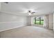 Spacious bedroom featuring neutral carpet, large window, and ceiling fan at 16 Pine Forest Dr, Haines City, FL 33844