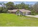 Expansive lawn with mature trees surrounds this single-story home with a neutral exterior and a tile roof at 16 Pine Forest Dr, Haines City, FL 33844