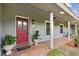 Close up of the charming front porch with brick flooring, potted plants, and a red front door at 16 Pine Forest Dr, Haines City, FL 33844