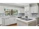 Bright kitchen featuring white cabinets, stainless appliances, tiled backsplash, kitchen island with cooktop, and hardwood floors at 16 Pine Forest Dr, Haines City, FL 33844
