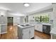 Open-concept kitchen features white cabinets, hardwood floors, tiled backsplash, island cooktop, quartz countertops, and stainless appliances at 16 Pine Forest Dr, Haines City, FL 33844