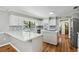 Open kitchen with white cabinets, an island with cooktop, stone countertops, and stainless steel appliances at 16 Pine Forest Dr, Haines City, FL 33844