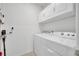 Bright laundry room featuring a washer, dryer, and overhead storage cabinets for organization at 1600 Spray Ter, St Cloud, FL 34771