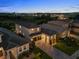 Aerial view showcasing the home's layout, landscaped yard, and neighborhood at twilight at 16049 Volterra Pt, Bella Collina, FL 34756