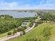 Scenic aerial view highlighting the community's tennis courts surrounded by lush trees and a beautiful lake at 16049 Volterra Pt, Bella Collina, FL 34756