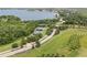An aerial view of tennis courts nestled among verdant landscaping next to a lake at 16049 Volterra Pt, Bella Collina, FL 34756