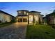 Charming two-story home featuring a manicured lawn and a long driveway with a two car garage at 16049 Volterra Pt, Bella Collina, FL 34756
