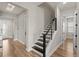 Hallway featuring wood flooring, a staircase with black steps, and neutral-colored walls at 16049 Volterra Pt, Bella Collina, FL 34756