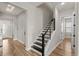 Bright hallway with a modern staircase, wood flooring, and access to multiple rooms at 16049 Volterra Pt, Bella Collina, FL 34756