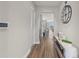 Inviting hallway showcasing hardwood floors and a decorative table with home decor accents at 16049 Volterra Pt, Bella Collina, FL 34756